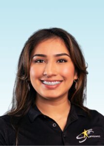 Smiling team member with braces wearing a black polo shirt