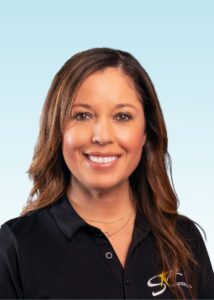 Smiling team member with long brown hair wearing a black polo shirt