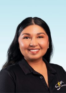 Smiling woman with long dark hair wearing a black polo shirt with embroidered logo