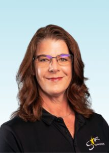 Smiling woman with auburn hair and glasses wearing a black polo shirt