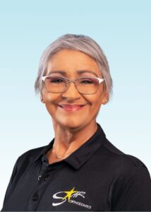 Smiling team member with short silver hair and glasses in a black branded polo shirt