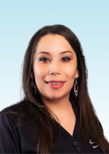 Smiling woman with long dark hair, dangle earrings, wearing black scrubs