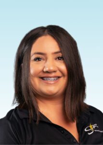 Smiling team member with braces wearing a black polo shirt with embroidered logo