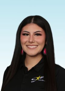 Smiling team member with long dark hair and pink earrings in a black branded polo