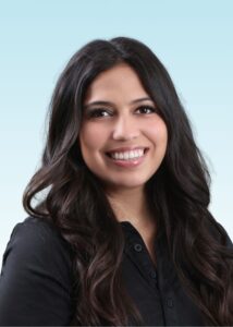 Smiling woman with long dark wavy hair wearing a black button-up shirt, professional headshot