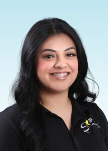 Smiling team member with braces and long dark hair, wearing a black polo shirt