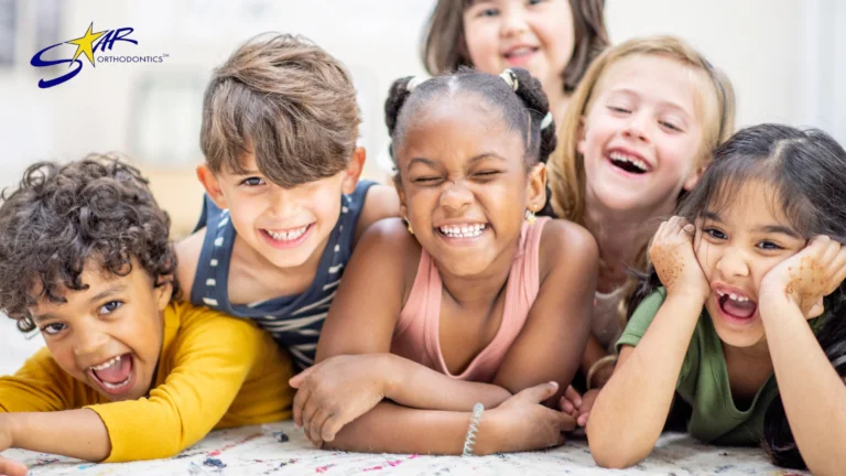 Group of six smiling children lying together and laughing