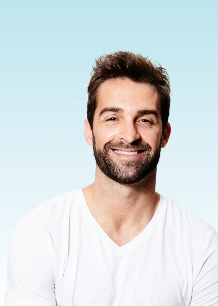 Smiling bearded man in white t-shirt against light blue background