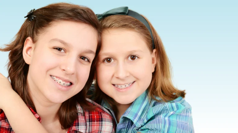 Two smiling teenage girls wearing braces in plaid shirts