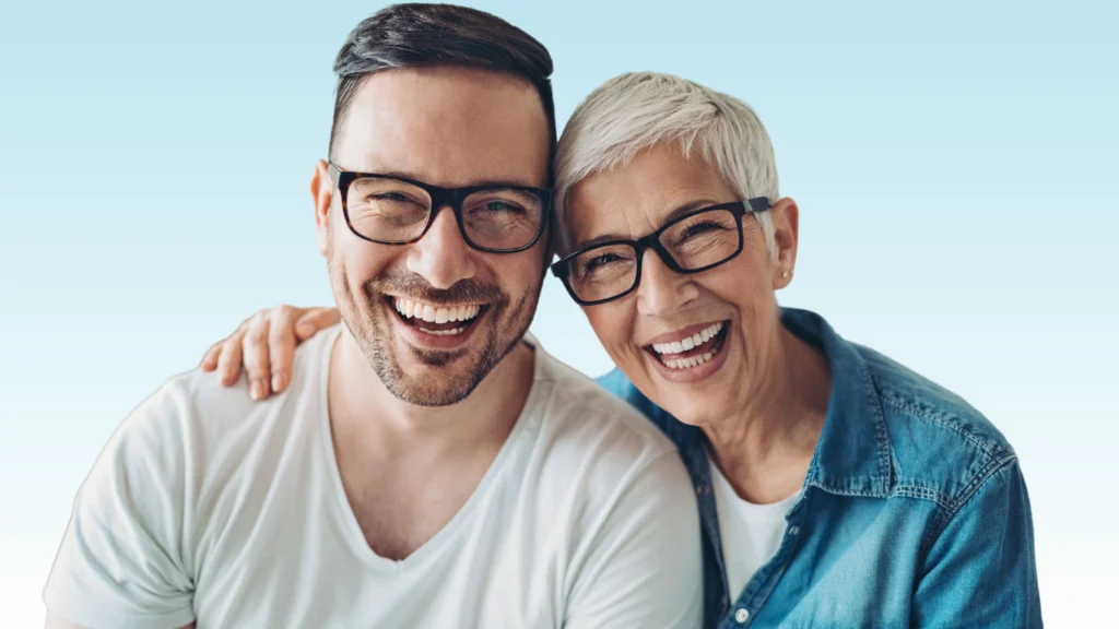 Smiling man and woman in glasses embracing, showing bright healthy teeth