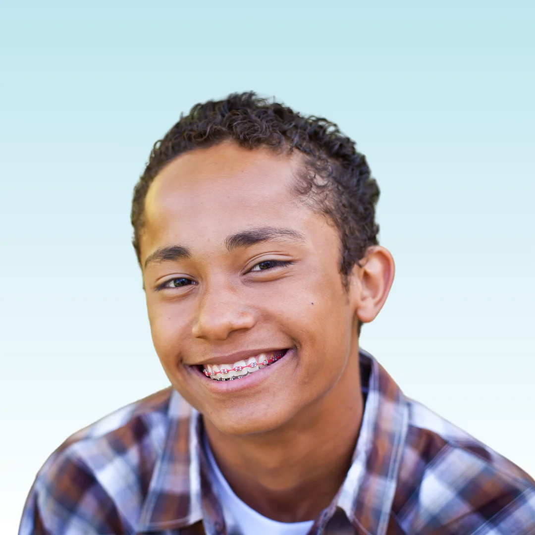 Smiling teen boy with metal braces wearing a plaid shirt