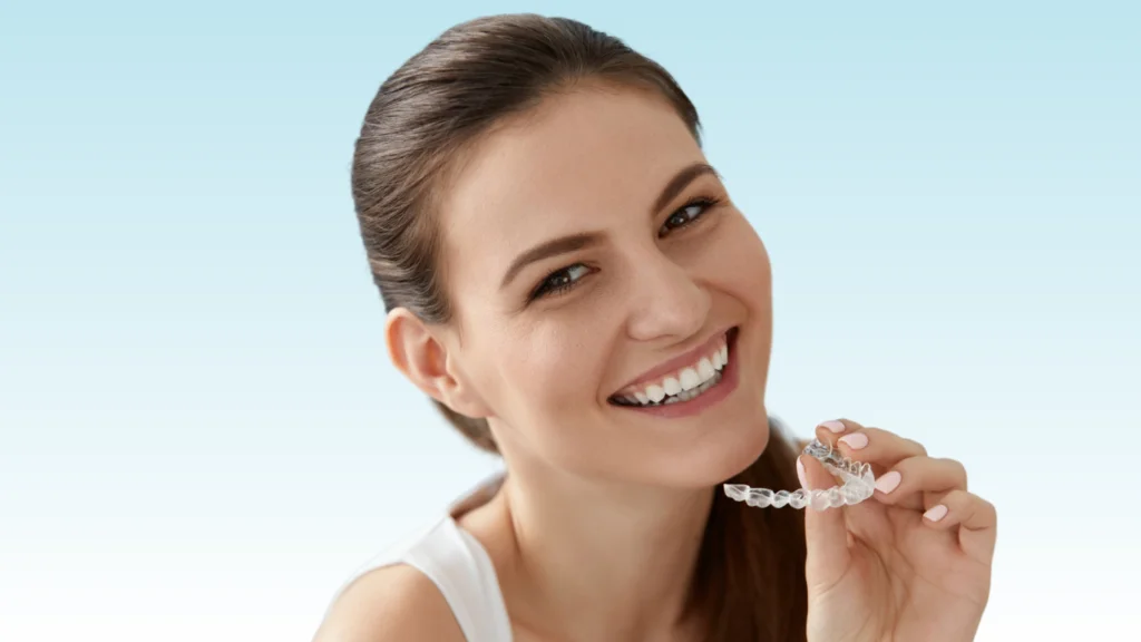 Smiling woman holding a clear aligner tray near her teeth