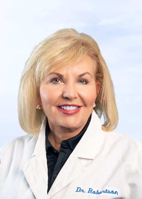 Dr. Robertson smiling in a white coat with embroidered name