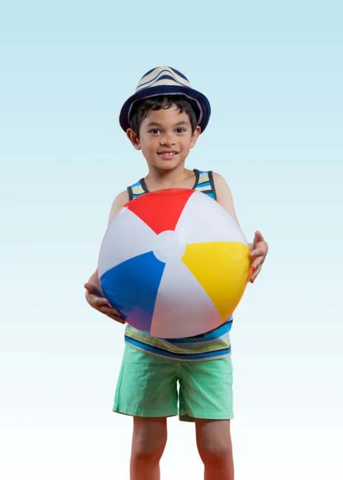 Smiling boy in a sun hat and tank top holding a colorful beach ball