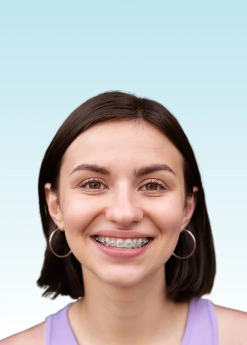 Smiling young woman with metal braces, hoop earrings, and a purple top